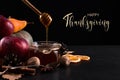 Thanksgiving greetings. Honey, dry leaves, apples and spices on a dark background, top view. Kaligraphic capital inscription Royalty Free Stock Photo