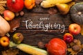 Thanksgiving greetings. Pumpkins, vegetables, nuts, dry leaves on a wooden background, top view. Kaligraphic capital inscription Royalty Free Stock Photo