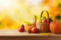 Thanksgiving holiday and autumn season concept with pumpkin, apples and fall leaves in basket on wooden table over autumn bokeh Royalty Free Stock Photo