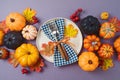 Thanksgiving holiday concept with plate, pumpkin and autumn leaves on purple background. Top view, flat lay