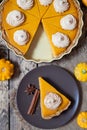 Thanksgiving homemade pumpkin pie with whipped cream and spices on rustic background, top view. Autumn Decoration