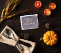 Thanksgiving Table Place Setting with Vintage Silverware, Lighted Candles, wheat and pumpkin, all on Dark Rustic Wood Table. The