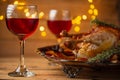 The Thanksgiving traditional turkey on the plate isolated on wooden background. The glasses with red wine are on the table. Yellow