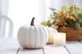 Thanksgiving white pumpkin and candle decorations on a white painted wood table. Halloween, Thanksgiving party concept