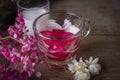 Thapthim krop, mock pomegranate seeds in coconut and syrup in the glass on the wood table there are flower and coconut milk placed