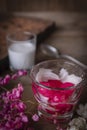 Thapthim krop, mock pomegranate seeds in coconut and syrup in the glass on the wood table there are flower, spoon and coconut milk