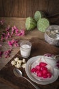 Thapthim krop, mock pomegranate seeds in coconut and syrup in the white bowl on the wood table there are flower, spoon, coconut