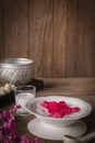 Thapthim krop, mock pomegranate seeds in coconut and syrup in the white bowl on the wood table there are flower, spoon, coconut
