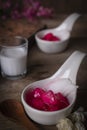 Thapthim krop, mock pomegranate seeds in coconut and syrup in the white spoon bowl on the wood table there are flower, spoon, same