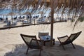 Thatch Roof Umbrella Screening the Sunlight. Beachfront Furniture Facing the Blue Ocean. Fence Barrier Dividing Area for