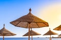 Thatched beach umbrella against the blue sky, hot sun and sea horizon. Wicker umbrellas on the beach. Rattan fungi from the sun on