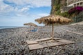 Thatched beach umbrellas and wooden beds at Ponta do Sol, Madeira island.