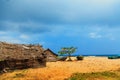 Thatched coconut leaf house or fishing hut and boats on tropical beach Royalty Free Stock Photo