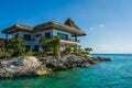 Thatched house on the rocks by the sea Royalty Free Stock Photo