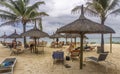 Thatched huts and beach chairs on tropical sandy beach Royalty Free Stock Photo