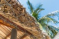 Thatched roof of bungalow with a net and palm on the background on the beach close-up Royalty Free Stock Photo