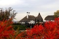 Thatched roof house in autumn. Cottage in rustic style in leaf fall. Rural landscape.Tourism and recreation in countryside Royalty Free Stock Photo