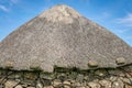 The thatched roof of a round house. metal cart wheel rims