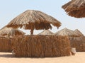 Thatched sunshades and sunbeds for tourists, on a yellow sand beach. Sun umbrellas on the Egyptian hotel beach. Royalty Free Stock Photo