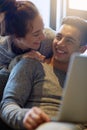 Thats amazing. an affectionate young couple surfing the net while relaxing on the sofa at home.