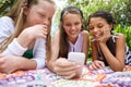 Thats so cute. A young girl showing her friends something on a cellphone while theyre relaxing outside. Royalty Free Stock Photo