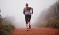 Thats what you call dedication. a woman running on a trail on a misty morning.