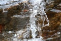 The thawing icicles with the falling water drop in the mountains