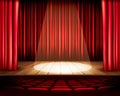 A theater stage with a red curtain, seats and a spotlight