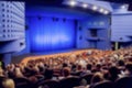 Theatre stage. Blue curtain. Defocused image, bokeh effect. People in the auditorium of the theater or concert hall