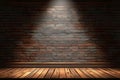 Theatrical lighting illuminates stage with brick wall and wooden floor