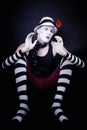 Theatrical mime with red flower sits