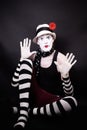 Theatrical mime with red flower sits on the floor