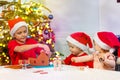 Thee kids decorate gingerbread house together in Santa hats Royalty Free Stock Photo