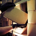 Theft of a box with a parcel in a warehouse. Man hands in gloves steal a box in a warehouse at night
