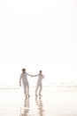 Their bond is strong. Full length shot of an attractive young couple dressed in white walking along a beach.