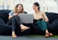 Their casual work environment keeps them innovative. two businesswomen using a laptop together while sitting on beanbags Royalty Free Stock Photo