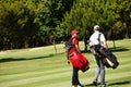 On their way to the next hole. two men carrying their golf bags across a golf course. Royalty Free Stock Photo