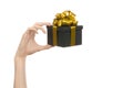 The theme of celebrations and gifts: hand holding a gift wrapped in a black box with gold ribbon and bow, the most beautiful gift Royalty Free Stock Photo