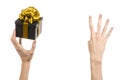 The theme of celebrations and gifts: hand holding a gift wrapped in a black box with gold ribbon and bow, the most beautiful gift Royalty Free Stock Photo