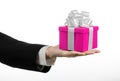 The theme of celebrations and gifts: hand holding a gift wrapped in pink box with white ribbon and bow, the most beautiful gift is Royalty Free Stock Photo