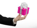 The theme of celebrations and gifts: hand holding a gift wrapped in pink box with white ribbon and bow, the most beautiful gift is Royalty Free Stock Photo