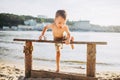 The theme is a child and summer beach vacation. A small Caucasian boy climbs up on a wooden bench on the river bank in a sunny sum Royalty Free Stock Photo