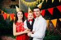 Theme children birthday party. Family father and mother holding son of one year on the background of greenery and festive decor, g