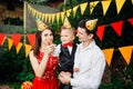 Theme children birthday party. Family father and mother holding son of one year on the background of greenery and festive decor, g