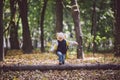 The theme children outdoor activities. Funny little baby Caucasian blond girl walks through forest overcoming obstacles, tree fell