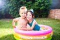 Theme is a children`s summer vacation. Two Caucasian children, brother and sister, sit in a perched round pool with water in the Royalty Free Stock Photo