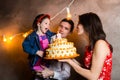 Theme family holiday childrens birthday and blowing out candles on large cake. young family of three people standing and holding 5