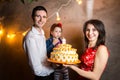 Theme family holiday childrens birthday and blowing out candles on large cake. young family of three people standing and