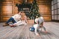 Family holiday New Year and Christmas. Young caucasian family mom dad son 1 year sit wooden floor near fireplace christmas tree on Royalty Free Stock Photo