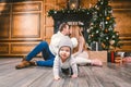 Family holiday New Year and Christmas. Young caucasian family mom dad son 1 year sit wooden floor near fireplace christmas tree on Royalty Free Stock Photo